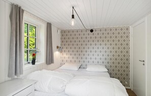 Cozy retreat with a single bed, bedside table, and window with curtains, set against a patterned backdrop.