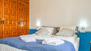 A neatly made bed with white and striped pillows, a blue blanket, and folded towels. - Nice home in La Cala de Mijas (La Cala de Mijas)