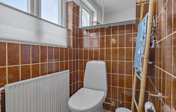 A bathroom with a toilet, a radiator, and a shower area.