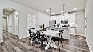 A modern kitchen with white cabinets, a stainless steel refrigerator, and a microwave.
