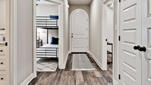A hallway with wooden flooring, a white door, and a white wall.