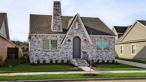 A brick house with a chimney, a front door, and a small porch.