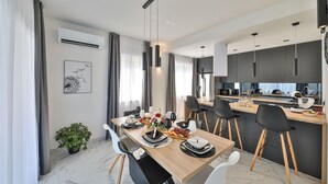 Una cucina e sala da pranzo moderne con pavimento in marmo, illuminazione a sospensione e un tavolo imbandito per sei persone.