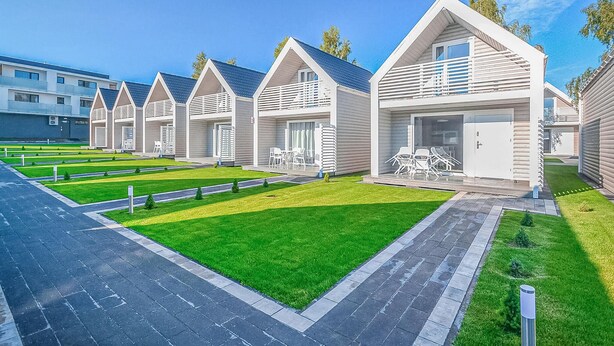 A row of modern, single-story cabins with attached garages, each featuring a small patio with outdoor seating. - 2 bedroom amazing home in Sianozety (Sianozety)