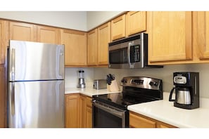 Enjoy cooking and meal preparation in this well-equipped kitchen with a refrigerator, microwave, toaster, stove, and coffee maker.