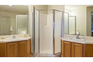 Modern bathroom with a glass-enclosed shower area, two sinks, and matching vanities.