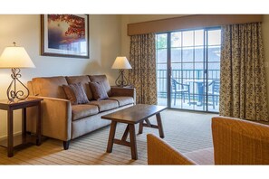 Relax in this inviting room with a comfortable sofa, armchair, and coffee table, plus a large window offering a view of the balcony.