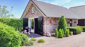 Une maison en briques avec un toit en tuiles, une porte d’entrée et un petit porche.