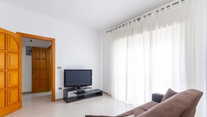 Una sala de estar con televisor, un sofá marrón y una puerta de madera.