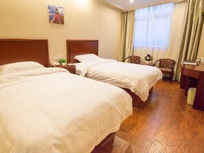 Une chambre d’hôtel avec deux lits, un plancher en bois, un bureau, une chaise et une fenêtre avec des rideaux.