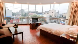 A hotel room with a large bed, a TV on a wooden stand, a sofa, and a balcony with a city view. - Greentree Inn Jiangsu Changzhou South Changwu Road (Changzhou)