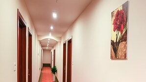 A hotel hallway with a red carpet, wooden doors, and a painting of a flower on the wall. - Greentree Inn Jiangsu Changzhou South Changwu Road (Changzhou)