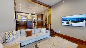 A living room with a sofa, a rug, and a painting of a snowy landscape. - Luxury Townhouse in the Heart of Sun Peaks Village (Sun Peaks)