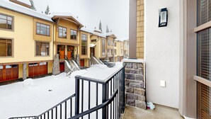 A multi-story building with a snow-covered ground and a staircase leading to the entrance. - Luxury Townhouse in the Heart of Sun Peaks Village (Sun Peaks)