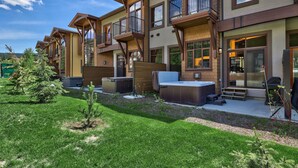 A multi-story residential building with balconies, outdoor seating, and a well-maintained lawn. - Luxury Townhouse in the Heart of Sun Peaks Village (Sun Peaks)