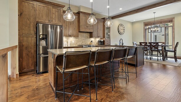 A modern kitchen with wooden cabinets, stainless steel appliances, and a central island with bar stools. - Luxury Townhouse in the Heart of Sun Peaks Village (Sun Peaks)