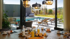 Ein Essbereich mit Blick auf einen Pool, ausgestattet mit einem Frühstücksbuffet mit Croissants, Obst und Getränken.