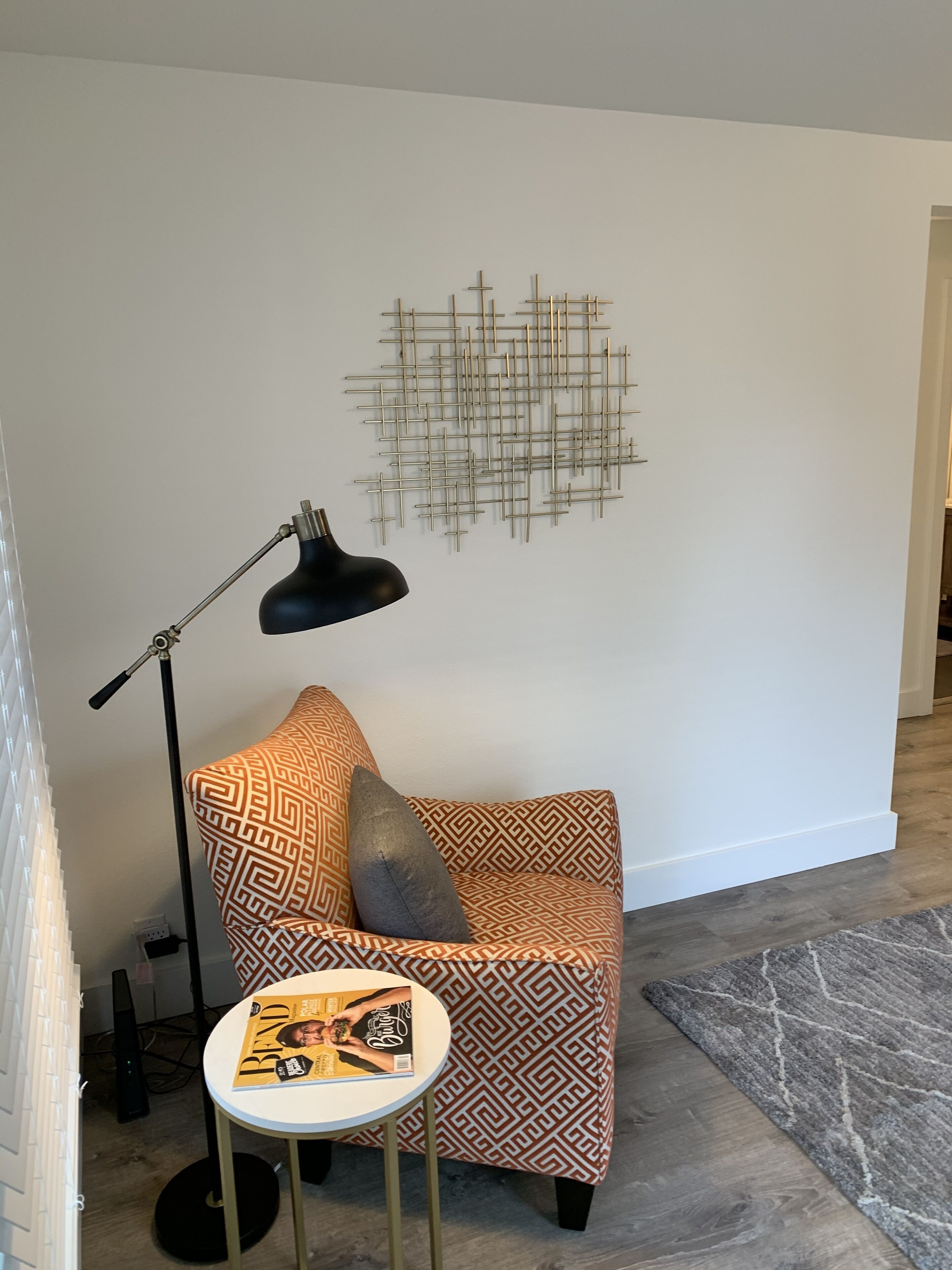 A modern living room with a patterned sofa, a floor lamp, and a decorative wall piece.