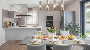 Una cucina moderna con zona pranzo, caratterizzata da un'isola centrale, elettrodomestici integrati e illuminazione a sospensione.