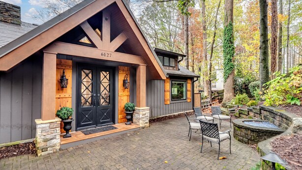 Une cabane rustique avec des fondations en pierre, une porte en bois sombre et une cheminée.