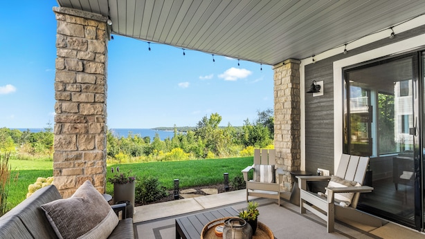 Un patio techado con un pilar de piedra, mobiliario exterior y vistas al paisaje.