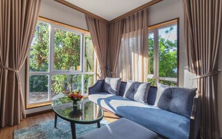 Un salón moderno con un sofá azul, una mesa de centro de vidrio y un jarrón de flores.