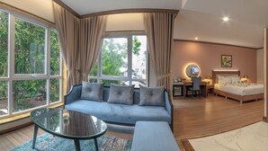 A modern hotel room with a large window, a sofa, a desk, and a bed. - Marigold Hotel Dalat (Xuan Huong - Da Lat)
