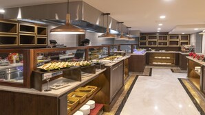 A buffet setup with various food items and a chef preparing food. - Marigold Hotel Dalat (Xuan Huong - Da Lat)