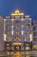 El Hotel Marigold, con una fachada clásica, varios pisos y un llamativo letrero iluminado.