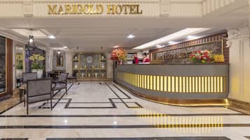 A hotel reception area with a marble floor, reception desk, and a reception sign.
