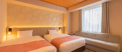 A hotel room with two beds, a sofa, a patterned wall, and a window with curtains.