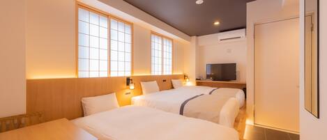 A hotel room with two beds, a wooden table, and a TV.