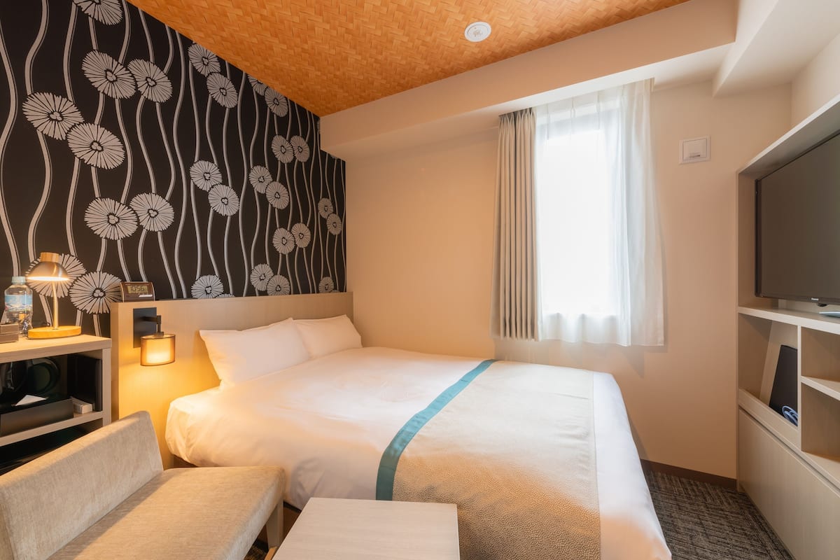 Una habitación de hotel con cama, televisión, escritorio y silla.