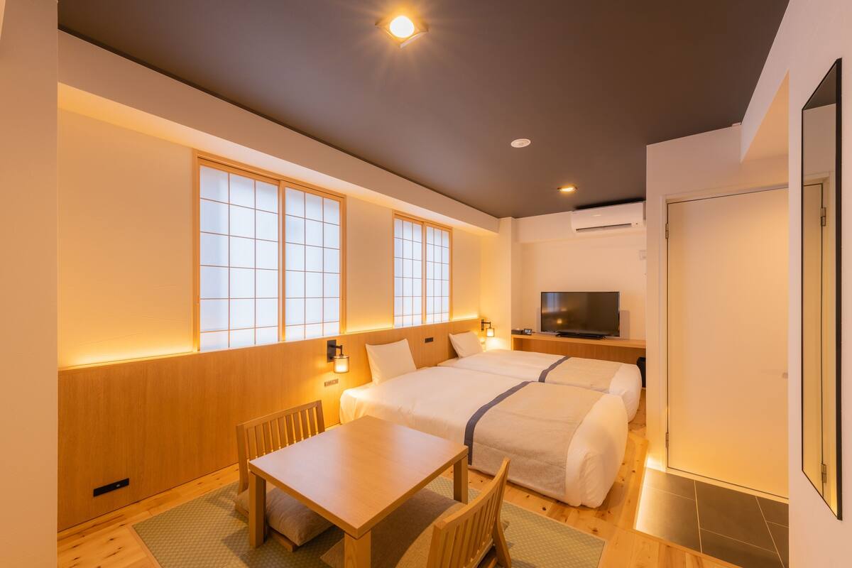 Habitación de hotel con dos camas, un televisor y una pequeña mesa.