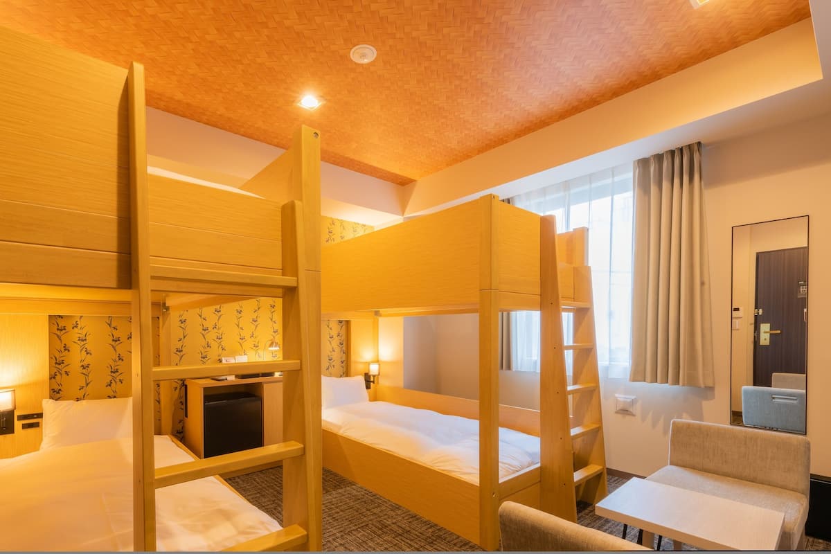 Una habitación de hotel con literas, un escritorio, una silla y una mesita.
