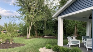 A well-maintained patio area with outdoor furniture, a hammock, and a lawn. - Beautiful newer construction 2021 home in town! (Saugatuck)