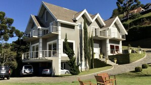 A two-story house with a garage, a driveway, and a lawn with outdoor furniture. - Wonderful house in Campos do Jordão  (SP)