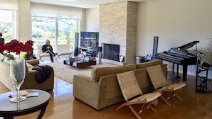 A spacious living room with a large TV, a piano, and a comfortable seating area. - Wonderful house in Campos do Jordão  (SP)