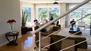 A spacious living area with a staircase, large windows, and a view of greenery. - Wonderful house in Campos do Jordão  (SP)