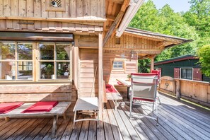 Une cabane en bois avec une terrasse, un banc, une table et un espace abrité.