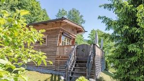 Eine Holzhütte mit Balkon, einem Fenster und einer Treppe, die zum Eingang führt.