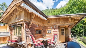 Eine Holzhütte mit einer Terrasse, einem Grill und einem Tisch mit Stühlen.