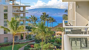 Un hotel moderno con vista sull'oceano e sulle montagne. Dispone di un balcone con mobili in vimini e un giardino curato con palme.