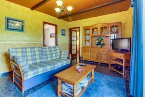 Sala de estar com sofá, mesa de centro, televisão e um armário com louças.