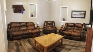 A living room with a brown leather sofa set, a wooden coffee table, and a hardwood floor.