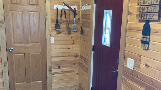 A wooden interior with a wooden door, a red door, and a wall sign that says "LIFE IS BETTER ON THE WATER".