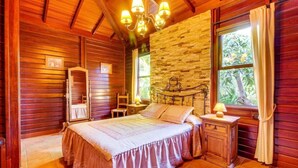 A wooden room with a bed, a stone wall, and a window with curtains. - Villa Mimosa, mountain views, pool, fast Wi-Fi, garden and terrace; parking available (Arafo)