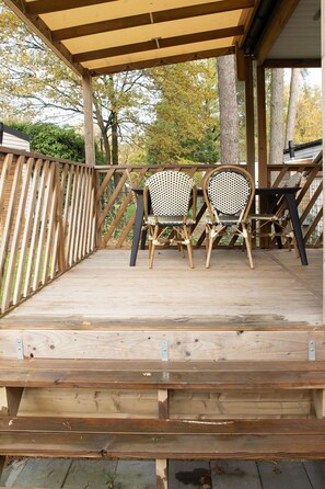 Une terrasse en bois avec deux fauteuils en osier et une pergola.
