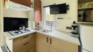 A compact kitchen with a gas stove, sink, and a microwave. - De Brenkberg by Interhome (Schinveld)