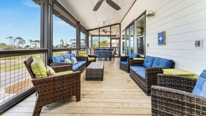 A covered outdoor seating area with wicker furniture and ceiling fans.